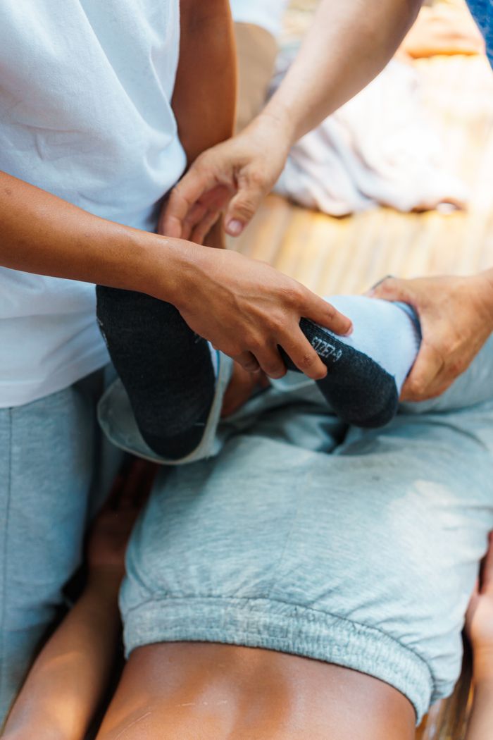 Two adults performing physical therapy on a patient in a rehabilitation session.