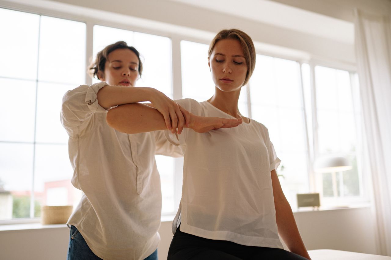 Two women participating in a therapy session indoors, focusing on relaxation and wellness.